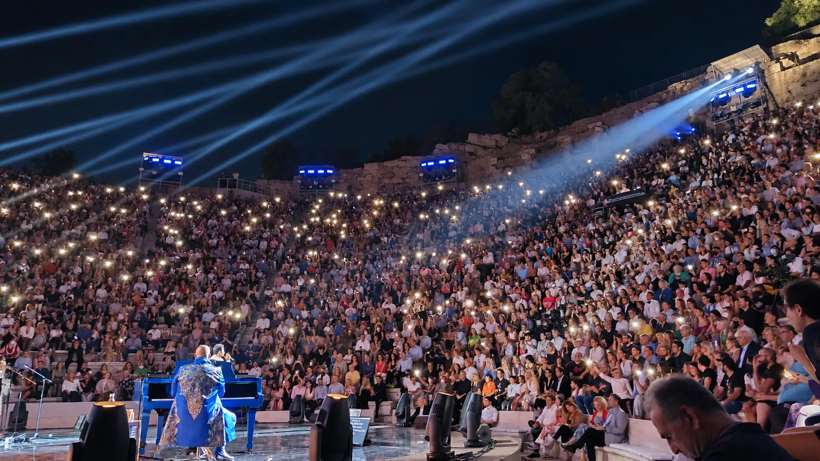 Large illuminated audience at an open-air theatre